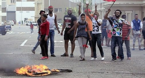Foreign nationals gesture after clashes broke out between a group of locals and police in Durban on April 14 ,2015 in ongoing violence against foreign nationals in Durban, South Africa. The attacks on immigrant-owned shops and homes in Durban's impoverished townships come three months after a similar spate of attacks on foreign-owned shops in Soweto, near Johannesburg. The Malawian government said on April 13, 2015 it would help repatriate its citizens from South Africa following an outbreak of xenophobic violence in the eastern port city of Durban that has left four people dead. AFP PHOTO/PHOTO STRINGER