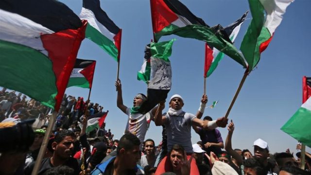 Demonstrators hold Palestinian flags during a protest marking the 71st anniversary of the Nakba in the southern Gaza Strip on May 15, 2019 [Reuters/Ibraheem Abu Mustafa]