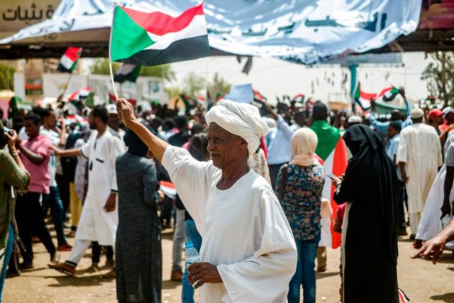 Sudanese woman holding up the countrys flag