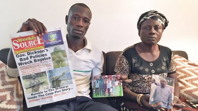 Abiri Angatimi Kenneth and Toboulayefa Jones hold photographs of their imprisoned father and husband