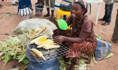 cropped a woman sells fresh grilled corn at a roadside market in nigerias BE1K69
