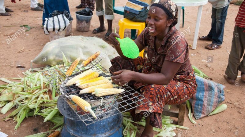 cropped a woman sells fresh grilled corn at a roadside market in nigerias BE1K69