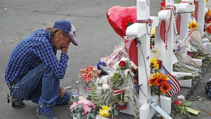 A man cries beside a cross at a makeshift memorial near the scene of an August 3 mass shooting at a shopping complex on August 6 2019 in El Paso Texas