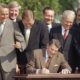 Congresspeople watch closely as President Ronald Reagan signs into law a landmark tax overhaul on the South Lawn of the White House in Washington