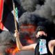 A demonstrator gestures as he stands close to burning tyres blocking a road during a protest in Baghdad, Iraq, October 2, 2019 [File: Thaier al-Sudani/Reuters]