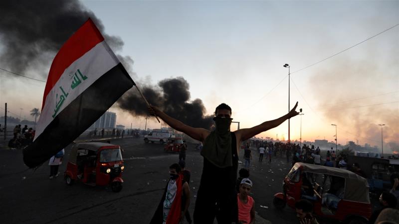 A demonstrator holds an Iraqi flag at a protest following four days of nationwide anti government protests