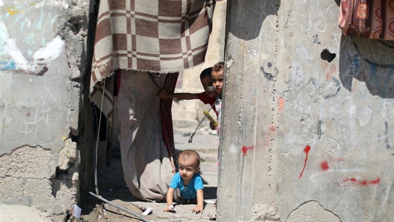 A Palestinian child crawls as other children look out of their family house in Al Shati refugee camp in Gaza City