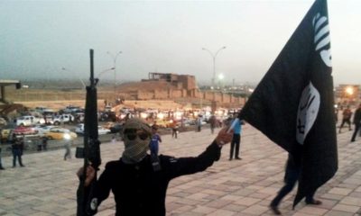 A fighter of the Islamic State of Iraq and the Levant holds an black flag and a weapon on a street in the city of Mosul Iraq