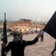 A fighter of the Islamic State of Iraq and the Levant holds an black flag and a weapon on a street in the city of Mosul Iraq