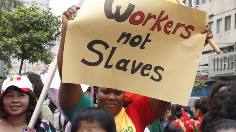 A migrant domestic worker holds up a placard during a parade in Beirut to support the rights of migrant domestic workers in Lebanon