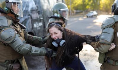 A demonstrator reacts as she is detained by riot policemen during a protest against Chiles government in Santiago Chile