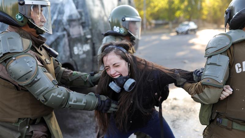 A demonstrator reacts as she is detained by riot policemen during a protest against Chiles government in Santiago Chile