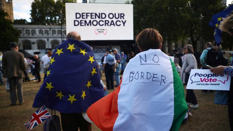A woman wearing an Irish flag and a man wearing an EU flag demonstrate in front of the parliament at Westminster in London on September 4 2019