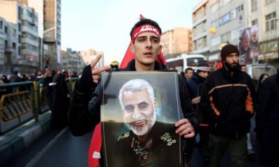 An Iranian man holds a picture of General Qassem Soleimani during his funeral procession in Tehran on January 6 2020