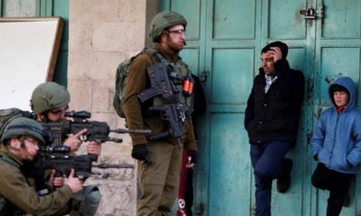 Palestinians watch as Israeli soldiers aim their weapons at a protest against the US President Donald Trumps Middle East plan in Hebron occupied West Bank on January 31 2020