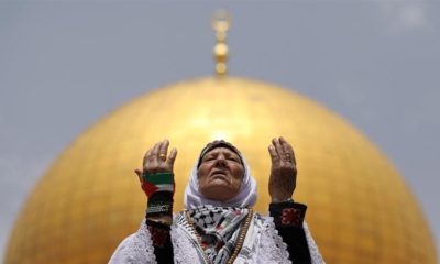 The Dome of the Rock is seen in the background as a Palestinian woman prays on the compound known to Muslims as al Haram al Sharif and to Jews as Temple Mount
