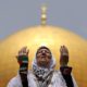 The Dome of the Rock is seen in the background as a Palestinian woman prays on the compound known to Muslims as al Haram al Sharif and to Jews as Temple Mount