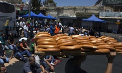 A youth walks by carrying loaves of bread as worshippers prepare to pray close to the Damascus Gate of the Old City in Jerusalem on July 25 2014