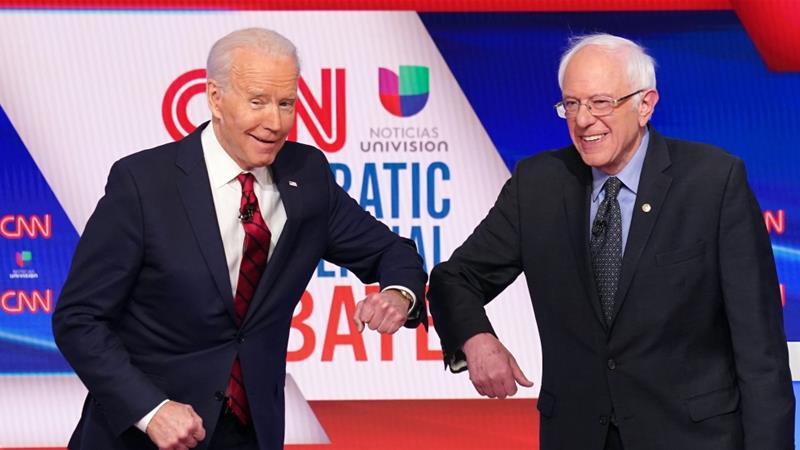 Joe Biden and Bernie Sanders do an elbow bump in place of a handshake before the start of the 11th Democratic candidates debate in Washington DC