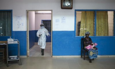 A health worker walks past a woman holding a baby at the maternity ward in the government hospital in Koidu Kono district in eastern Sierra Leone on December 20 2014