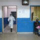 A health worker walks past a woman holding a baby at the maternity ward in the government hospital in Koidu Kono district in eastern Sierra Leone on December 20 2014