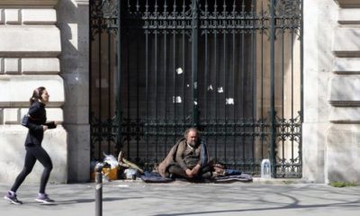 A woman runs as a homeless man looks on during the lockdown of coronavirus in Paris on March 27 2020