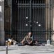 A woman runs as a homeless man looks on during the lockdown of coronavirus in Paris on March 27 2020