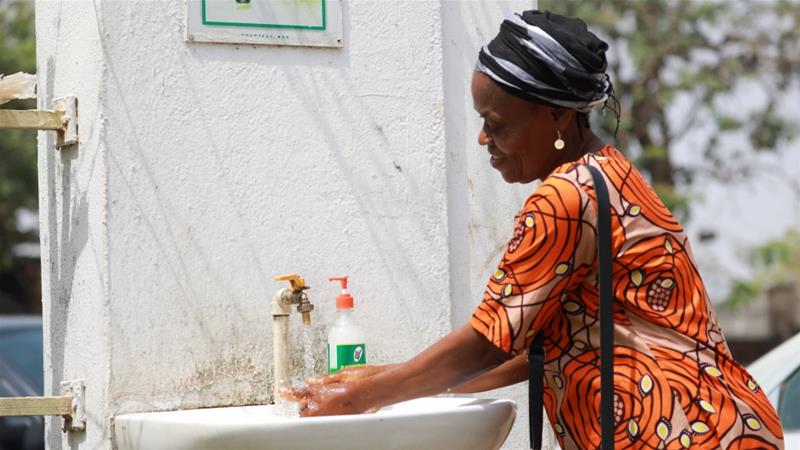 A woman washes her hands amid the coronavirus outbreak by the gate of Maitama General Hospital in Abuja Nigeria on March 19 2020