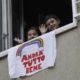 Children wave after placing a banner reading Everything will be all right out of the window of their apartment in Rome Italy on March 13 2020
