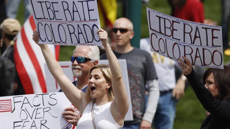 People protest against a state at home order issued by Colorado Governor Jared Polis to curb the coronavirus outbreak on April 19 2020 in Denver US
