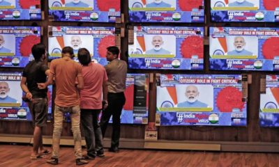 People watch Indian Prime Minister Narendra Modi address the nation amid concerns about the spread of coronavirus inside a showroom in Ahmedabad India on March 19 2020