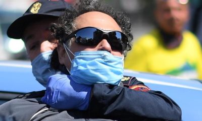 Police detain a man who was putting red banners on memorial plaques dedicated to Italian partisans on Liberation Day amid the lockdown in Milan Italy on April 25 2020