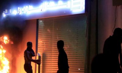 A demonstrator is seen next to a burning fire in front of a bank during a protest against growing economic hardship in Sidon Lebanon pm April 29 2020