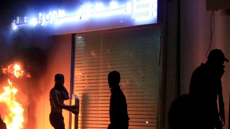 A demonstrator is seen next to a burning fire in front of a bank during a protest against growing economic hardship in Sidon Lebanon pm April 29 2020