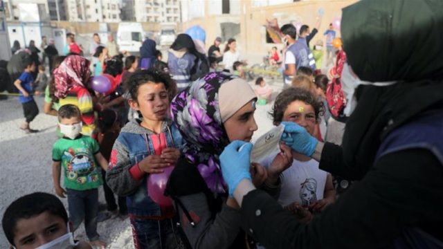 A volunteer distributes face masks to internally displaced children amid concerns over the spread of COVID 19 at an IDP camp in Idlib Syria May 19 2020