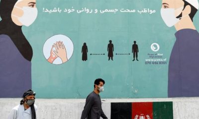 An Afghan man wearing a protective face mask walks past a painted wall amid the coronavirus pandemic in Kabul Afghanistan