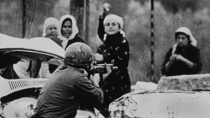 An Israeli soldier aims his rifle at a Palestinian woman holding a rock during a demonstration in which one Palestinian youth was shot dead in Gaza on February 29 1988