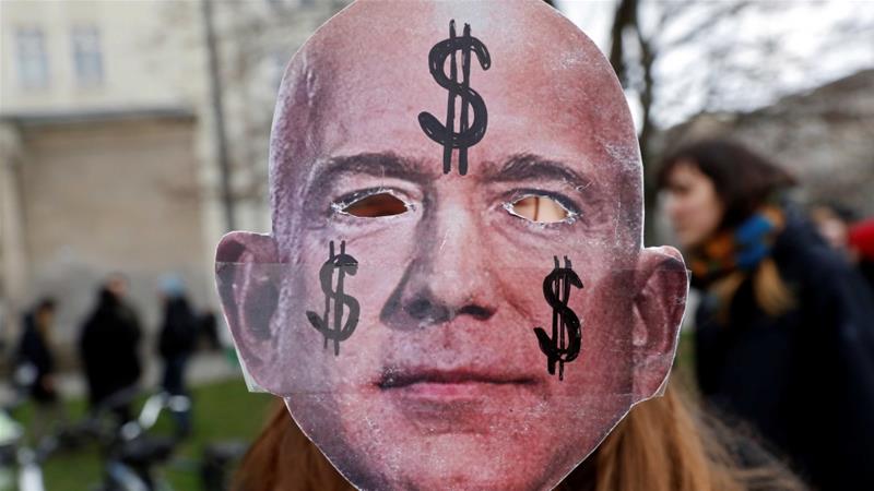 An activist holds up a mask depicting Amazon founder Jeff Bezos during a protest against the opening of a new Amazon office in Berlin Germany on February 22 2020