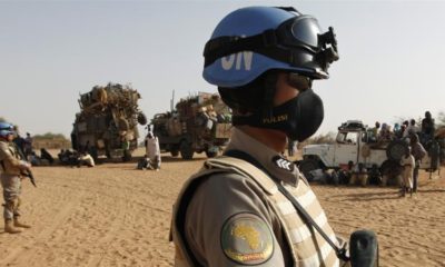 Two UNAMID peacekeepers patrol by trucks loaded with new arrivals of displaced Sudanese at Zamzam refugee camp outside the Darfur town of al Fasher Sudan on March 23 2009