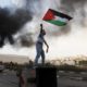 A Palestinian man waves the national flag during a protest against Israels operations in Gaza Strip near the West Bank city of Ramallah on Nov 18 2012