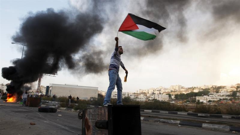 A Palestinian man waves the national flag during a protest against Israels operations in Gaza Strip near the West Bank city of Ramallah on Nov 18 2012