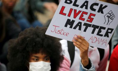 A woman wearing a protective face mask holds a banner as she attends a protest against police brutality at Place de la Republique in Lille France June 10 2020