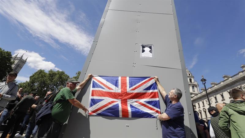 Members of far right Football Lads Alliance hold a British flag in front of the covered statue of Winston Churchill in Parliament Square London June 13 2020