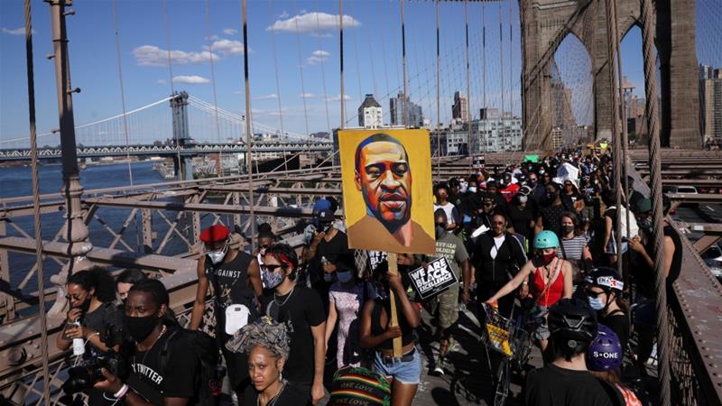 People hold signs on Brooklyn Bridge during a protest against police brutality and racism in the aftermath of the death of George Floyd in New York US on June 13 2020