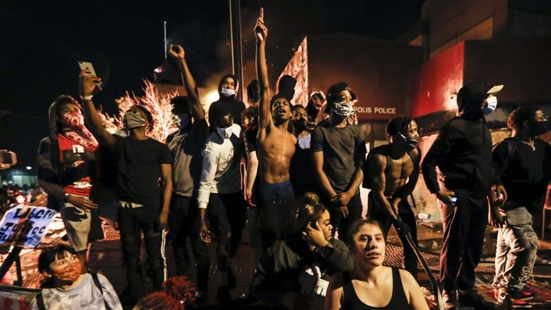 People protest the death of George Floyd in police custody outside of the burning Minneapolis 3rd Police Precinct building on May 28 2020 in Minneapolis US