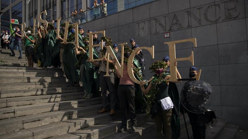 Climate protesters wearing masks to protect themselves against COVID 19 form the word Resilience next to a police security line in Brussels Belgium on June 27 2020