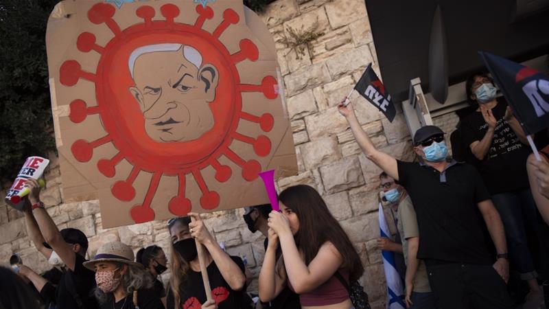 A protester holds a sign depicting Prime Minister Benjamin Netanyahu during a demonstration outside his residence in Jerusalem on July 31 2020