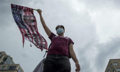 A protester waves an American flag with Black Lives Matter spray painted on it near the White House in Washington June 19 2020