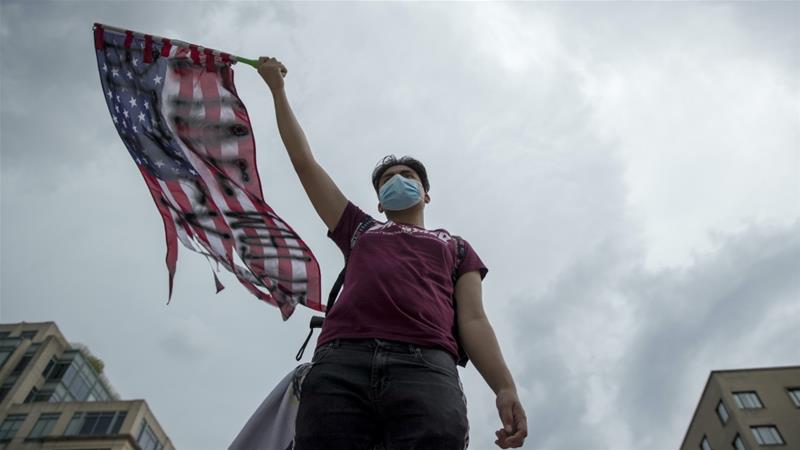 A protester waves an American flag with Black Lives Matter spray painted on it near the White House in Washington June 19 2020