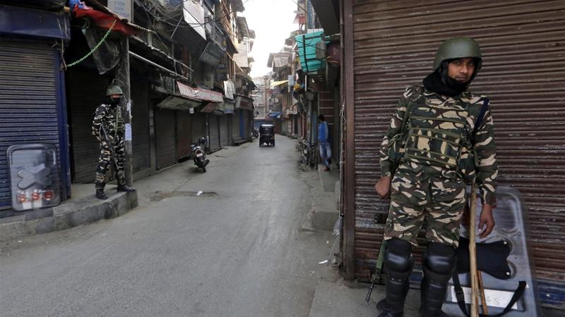 Indian security force personnel stand guard in front closed shops in a street in Srinagar October 30 2019